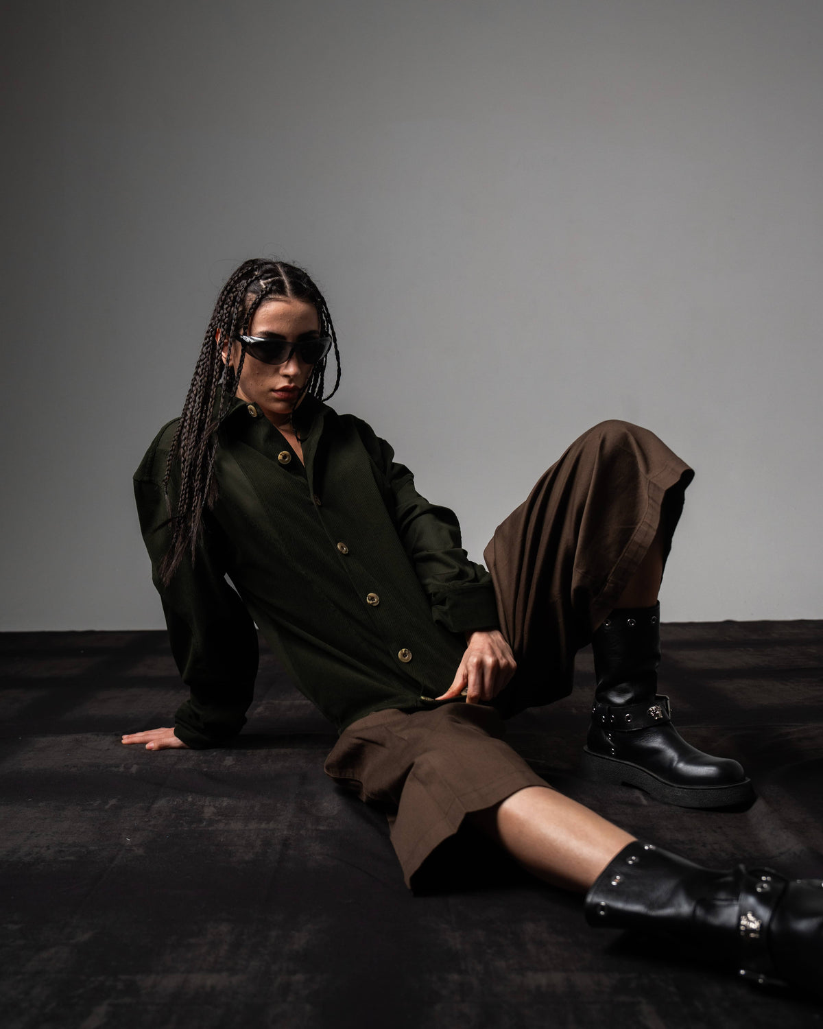Seated look of a woman styling a dark olive textured oversized button up shirt