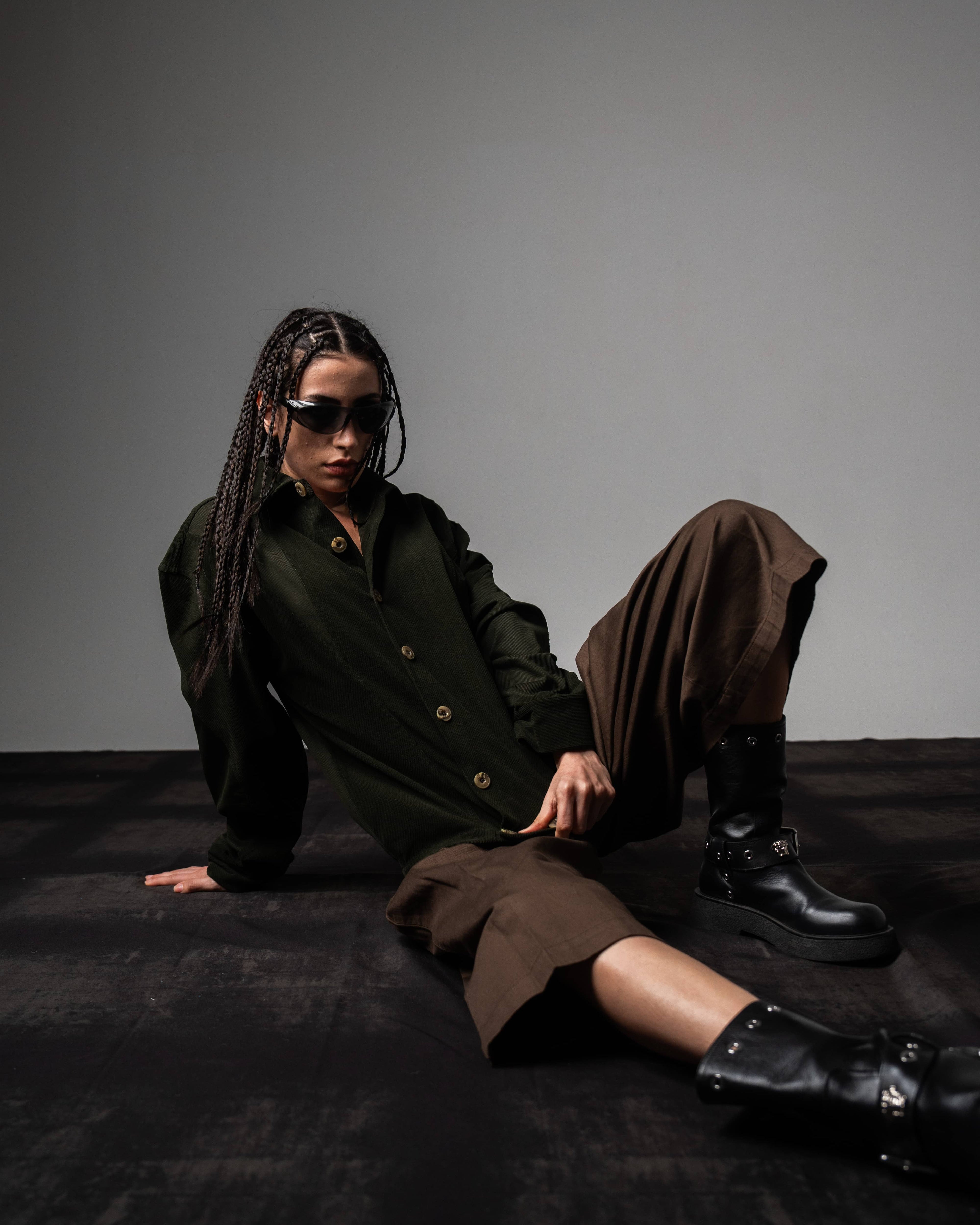 Seated look of a woman styling a dark olive textured oversized button up shirt