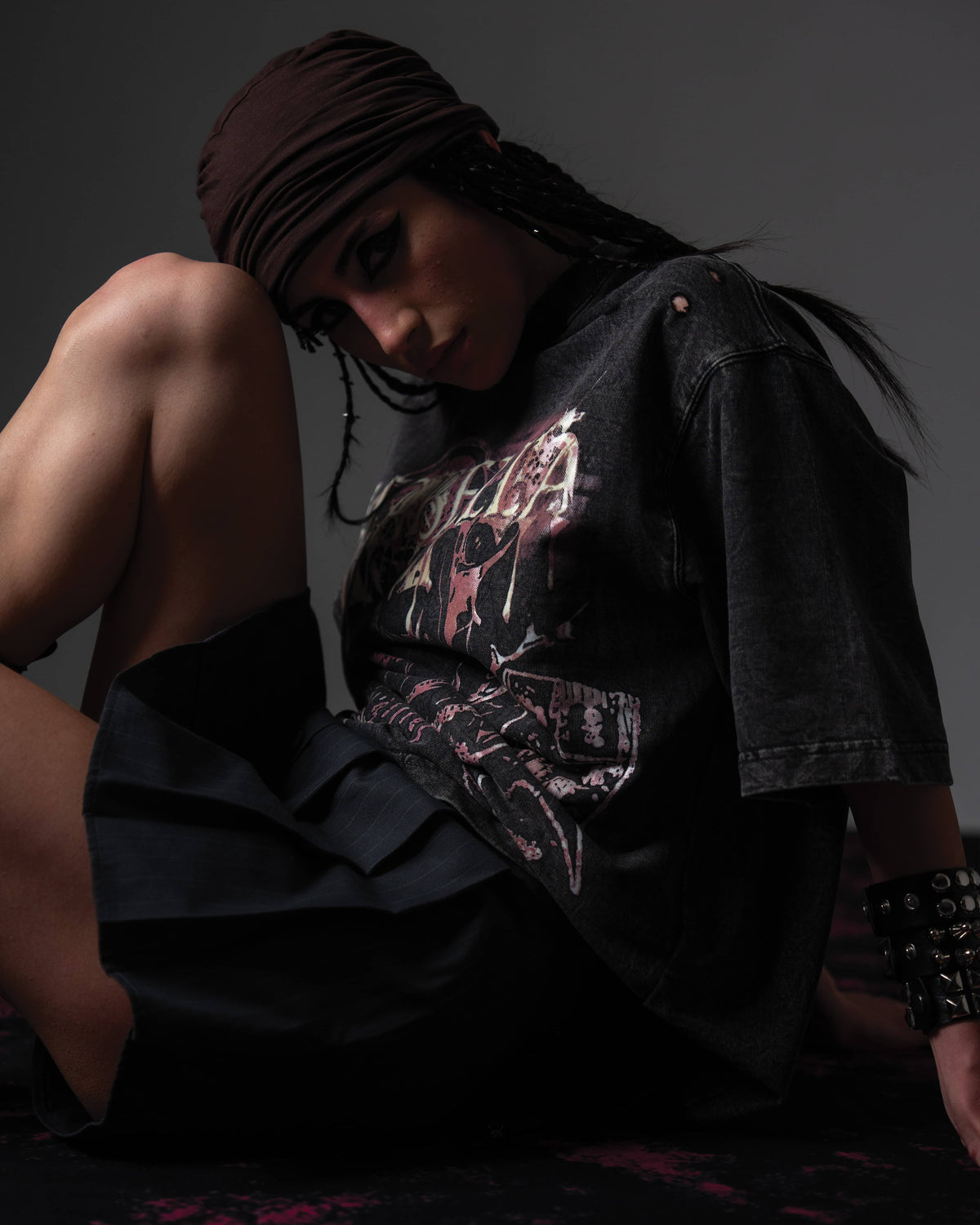 Studio shot of a woman wearing a black skull graphic t-shirt paired with a mini skirt and boots
