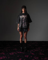Front full view of a woman styling an oversized washed black t-shirt with a skull graphic print