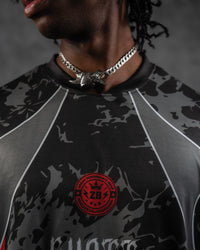 Extreme close-up of the ribbed crewneck collar paired with a silver cuban chain, featuring the red performance crest badge