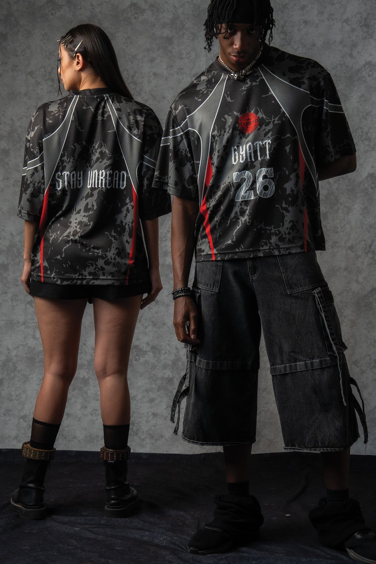 Studio campaign shot of a male and female model styling matching ZBRIX_26 oversized jerseys with tactical combat boots